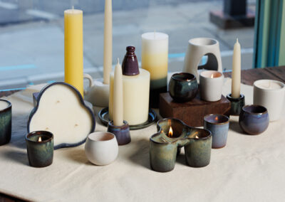 Waxman ceramic candle holders and candles arranged on an off white cloth.